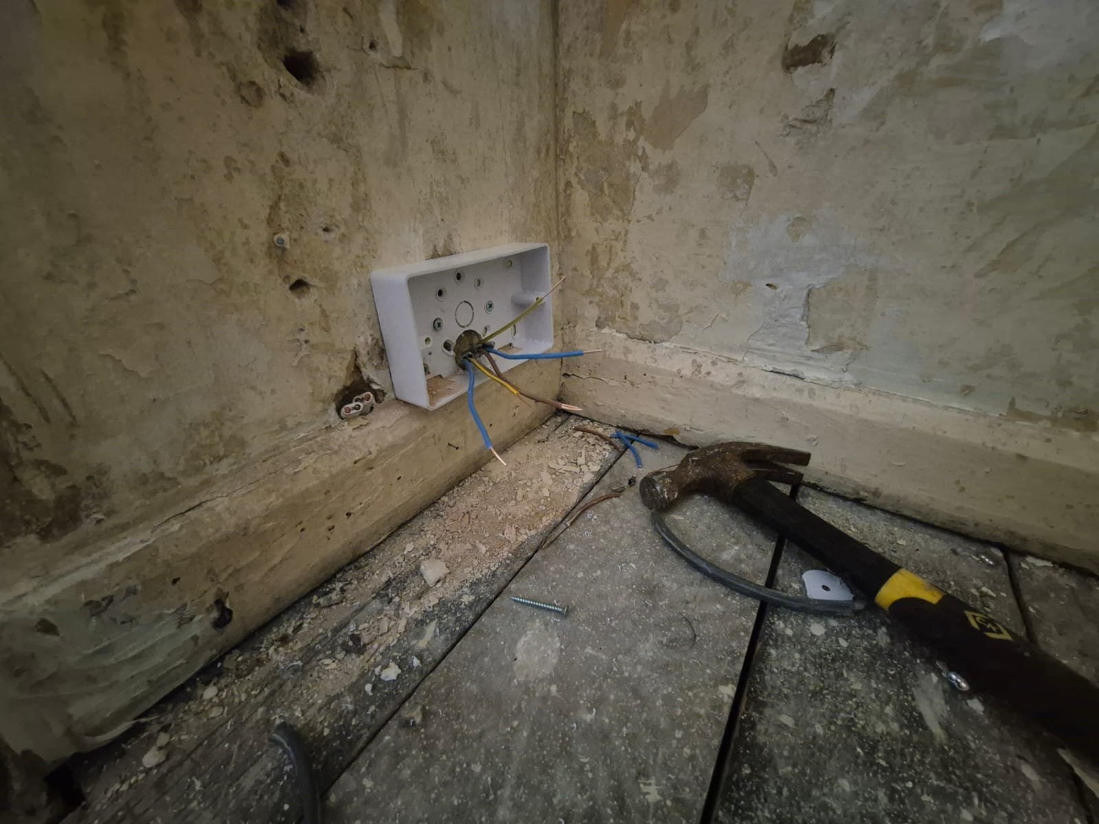 Electrician checking an older socket circuit during a rewiring survey in Brighton
